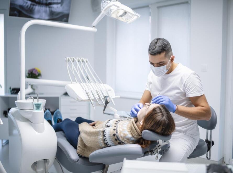 طبيب يفحص أسنان مريض على كرسي العلاج داخل عيادة أسنان